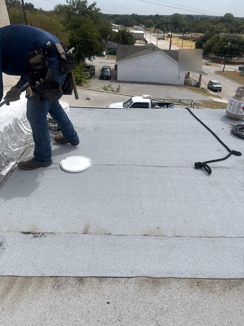 Roofer applying a granulated flat-roof membrane on a commercial building roof
