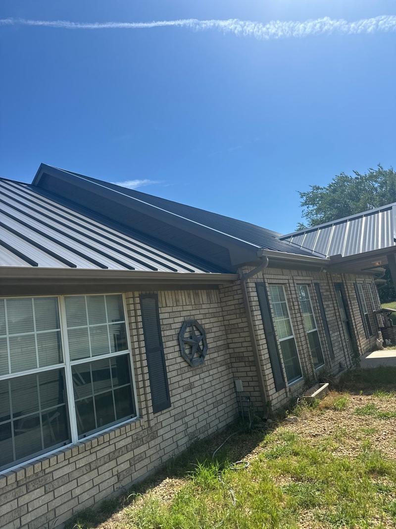 Corner view of a charcoal standing seam metal roof on a brick ranch home in Wise County