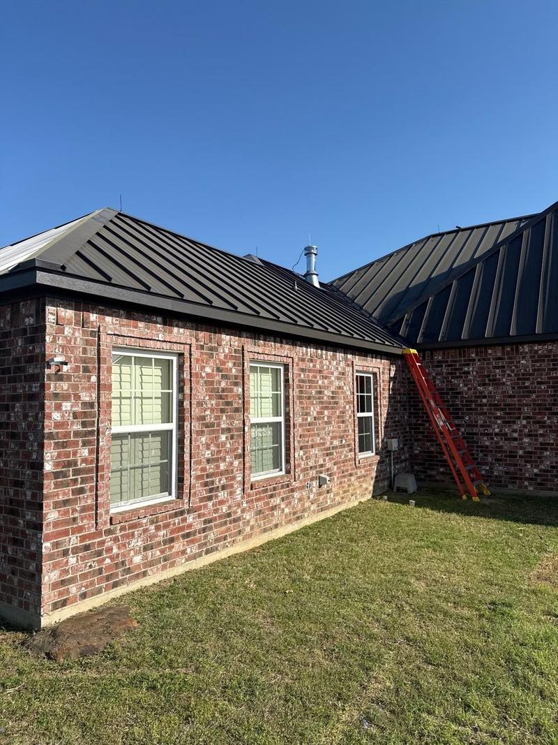 Side elevation of a brick home with multiple hips in standing seam metal