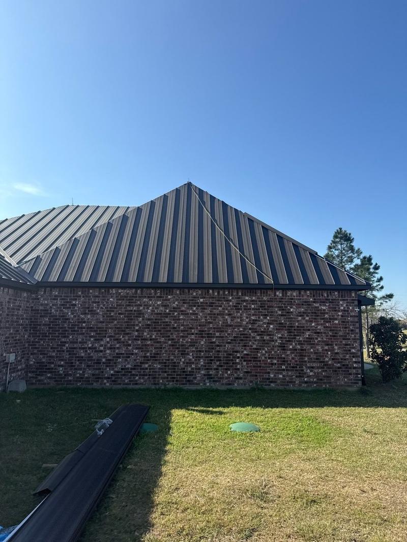 Hip roof in dark standing seam metal on a red brick wall
