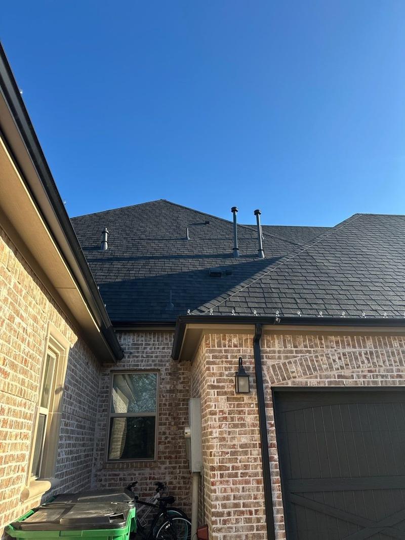 Charcoal shingle roof and gutters at the garage of a brick home