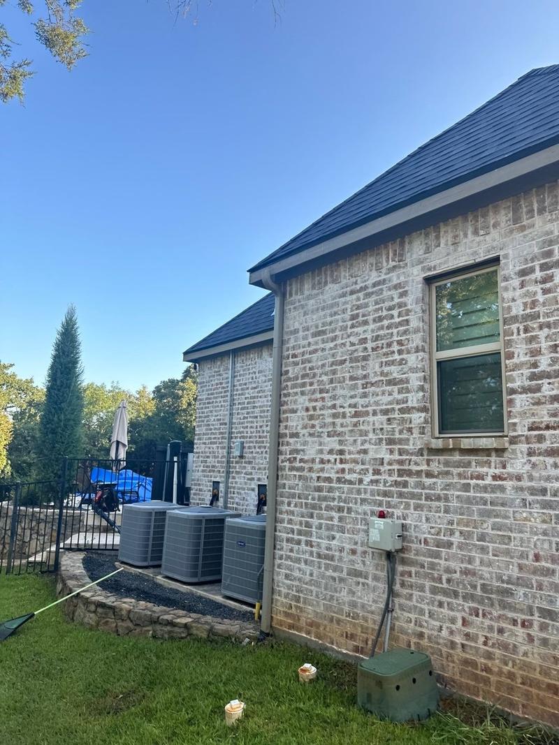 Steep-slope charcoal shingle roof on the side of a two-story brick home